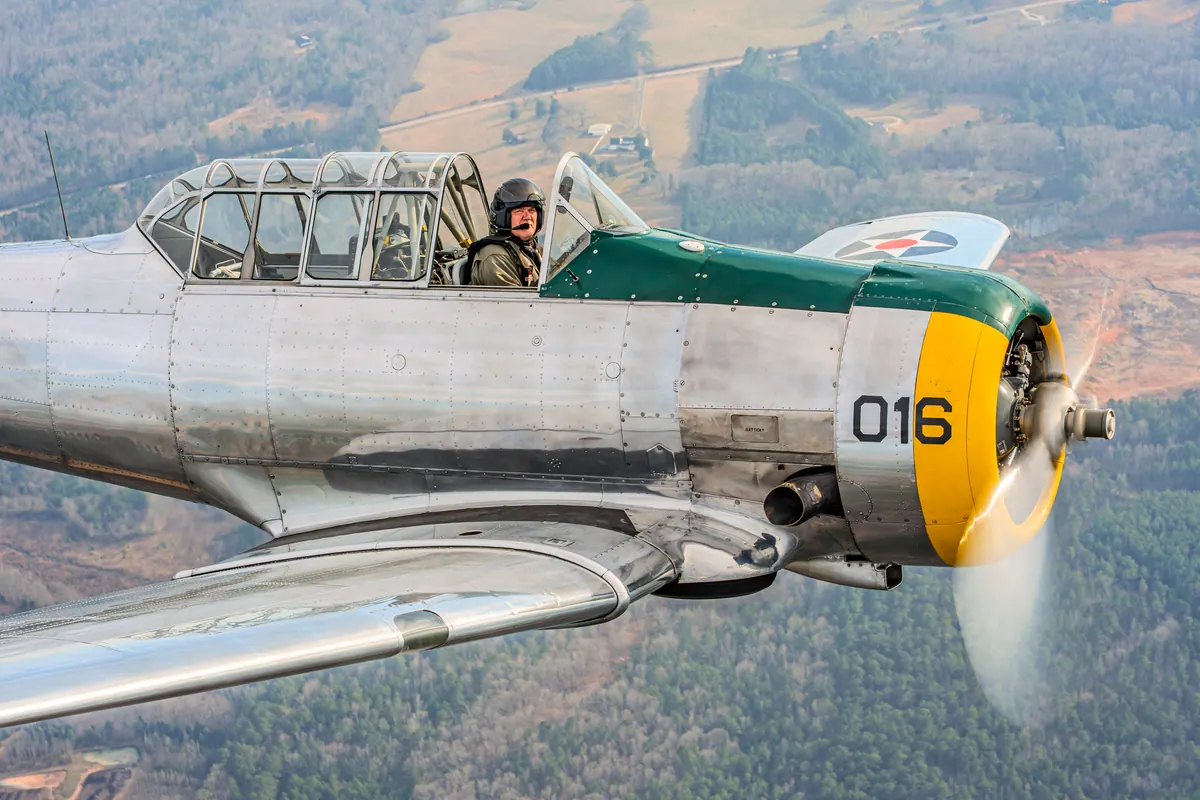 Close view of the silver trainer's yellow nose, a vapour vortex curling off the propeller